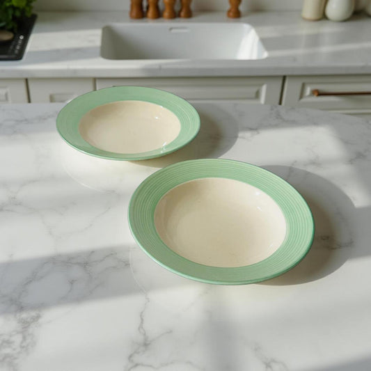 Two green-rimmed bowls on a marble countertop with a kitchen background.