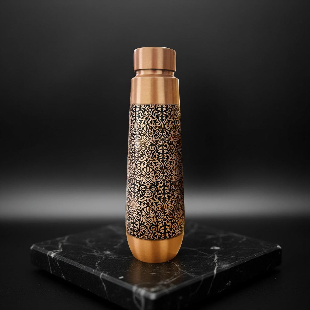Copper water bottle with intricate patterns on a black marble surface