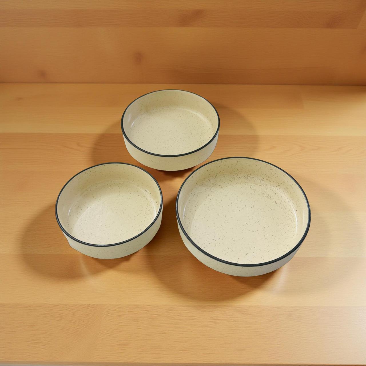Three ceramic bowls with black rims on a wooden surface