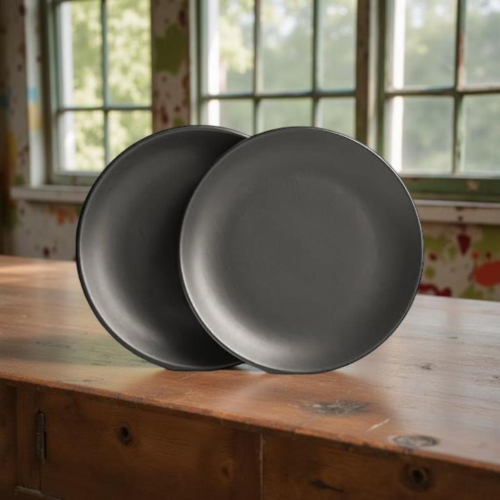 Two gray plates on a wooden surface with a window in the background