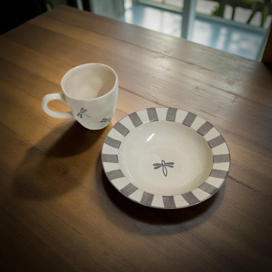 Ceramic cup and bowl with dragonfly design on a wooden table