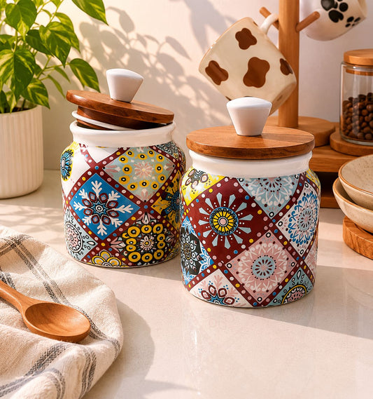 Two ceramic jars with colorful patterns and wooden lids on a kitchen counter.