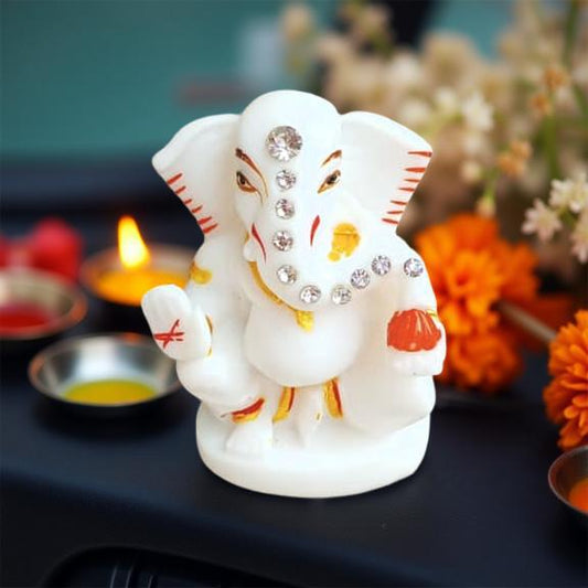 Decorative figure of Ganesha with embellishments on a dark surface with floral decorations.