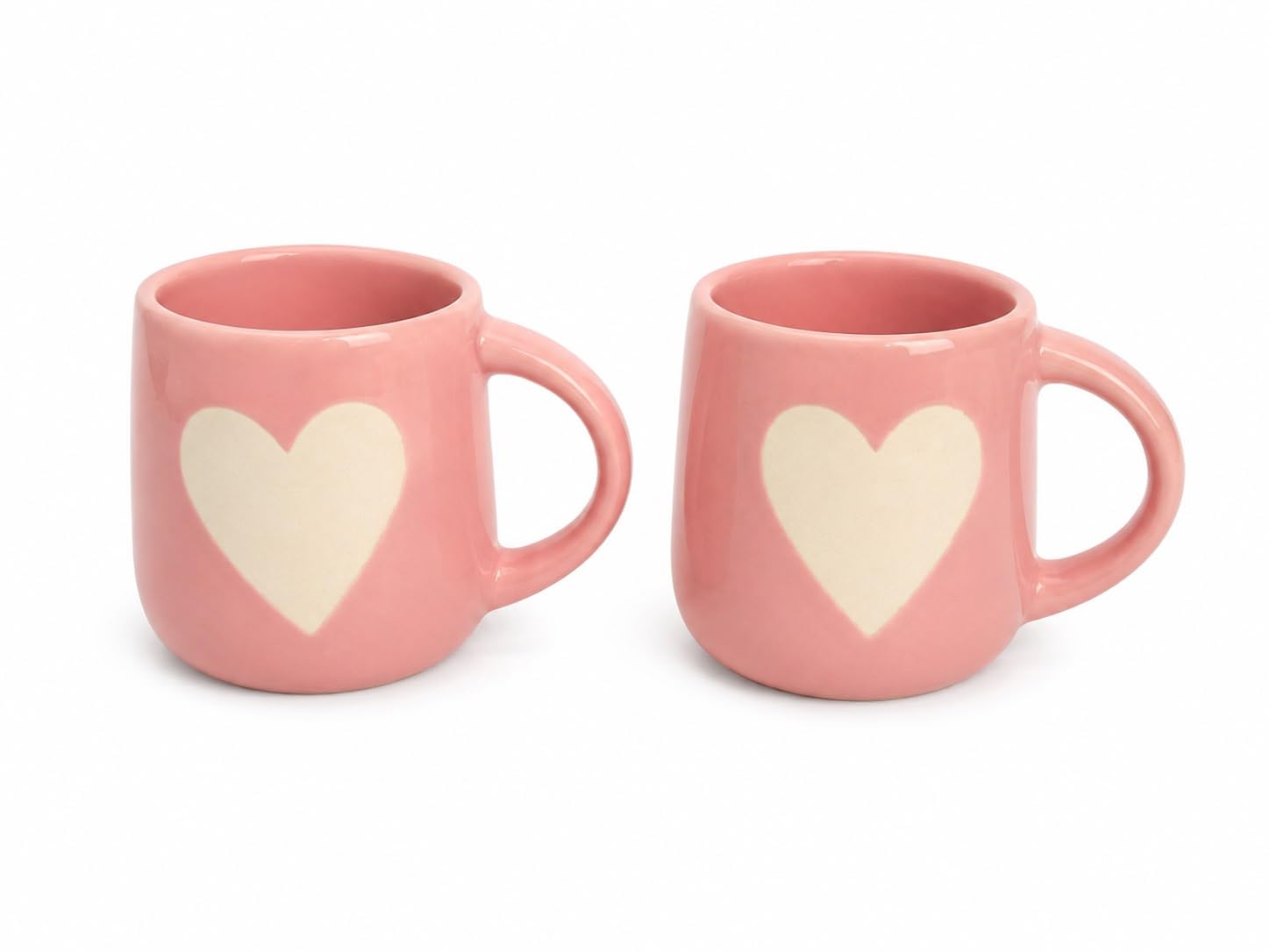 Two pink ceramic mugs with cream-colored heart designs on the front, displayed side-by-side on a white background.