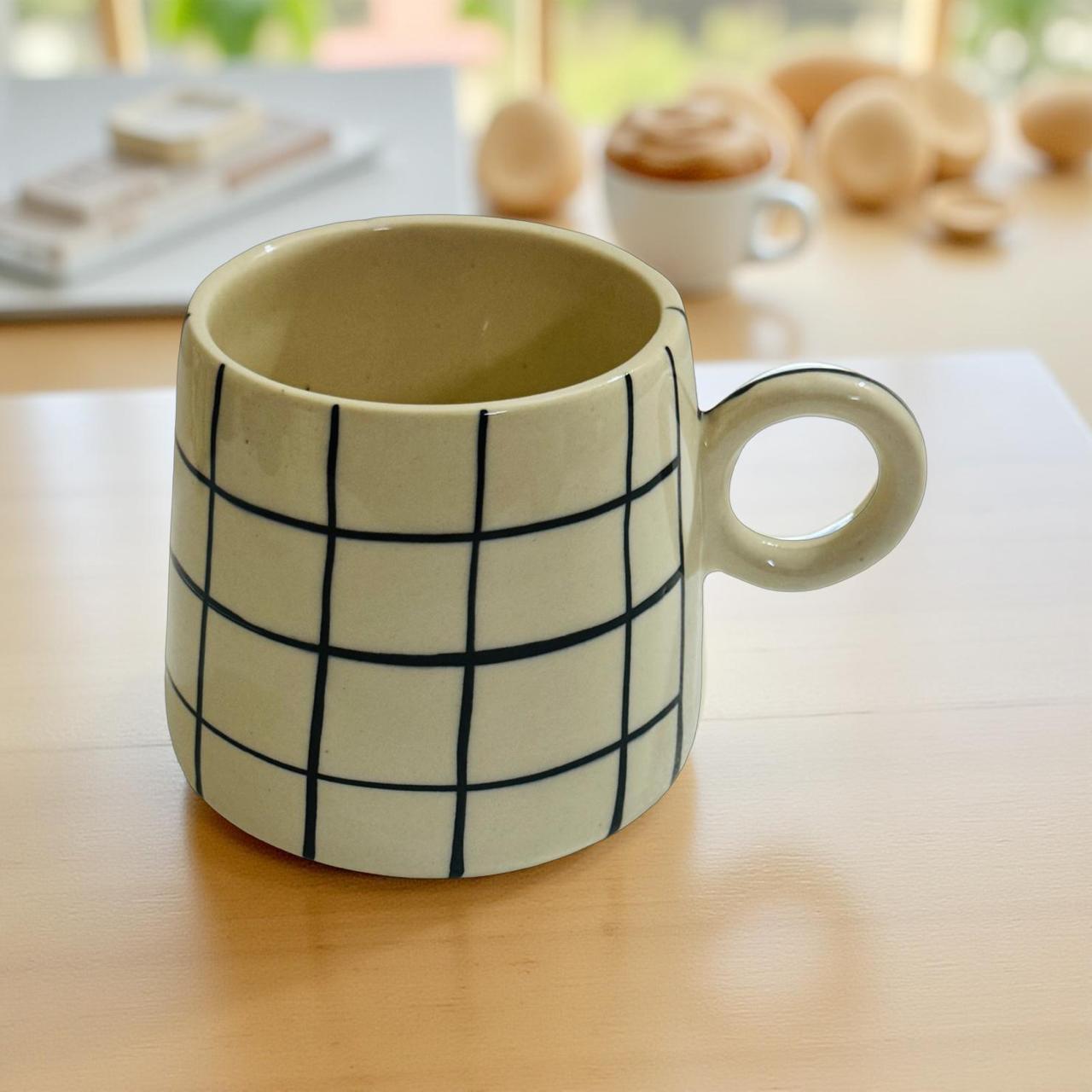 Ceramic mug with grid pattern on a wooden surface