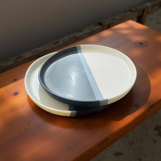 Two ceramic plates stacked on a wooden surface with a rustic background