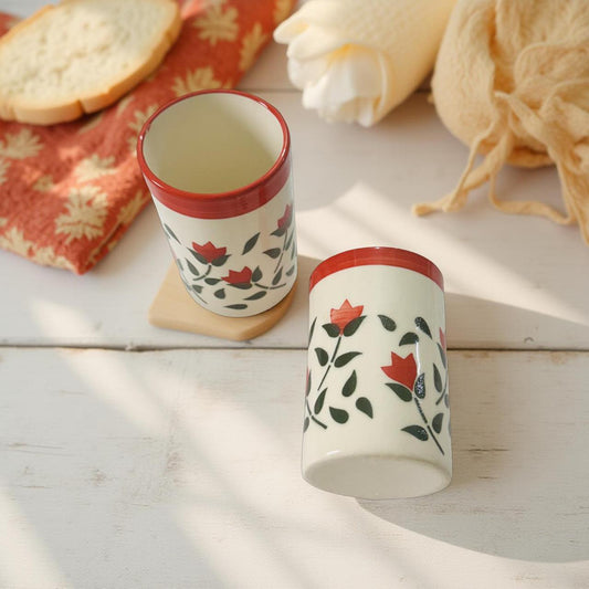 Two ceramic glasses with floral design on a wooden surface