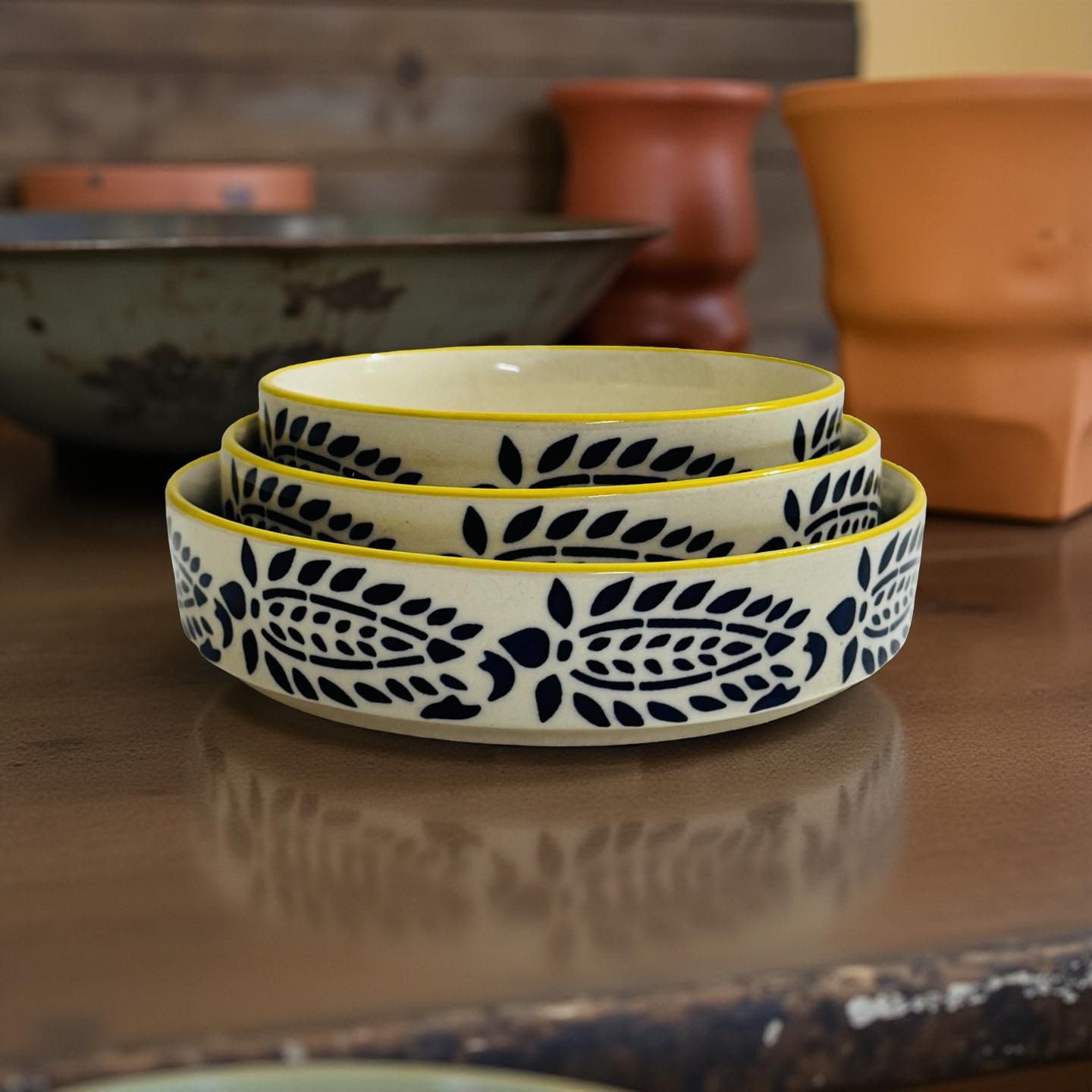 Set of three ceramic bowls with floral patterns on a reflective surface