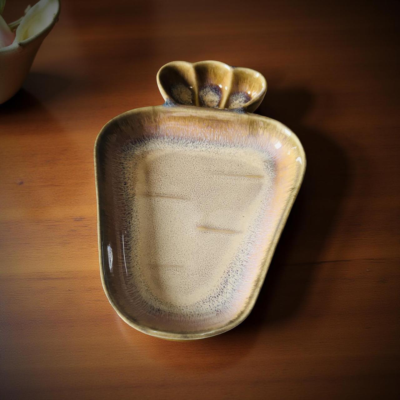 Ceramic leaf-shaped dish on a wooden surface