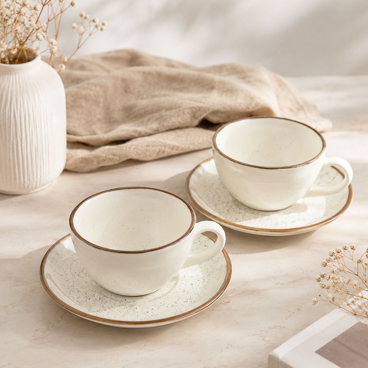 Two ceramic tea cups with saucers on a light surface with a neutral background