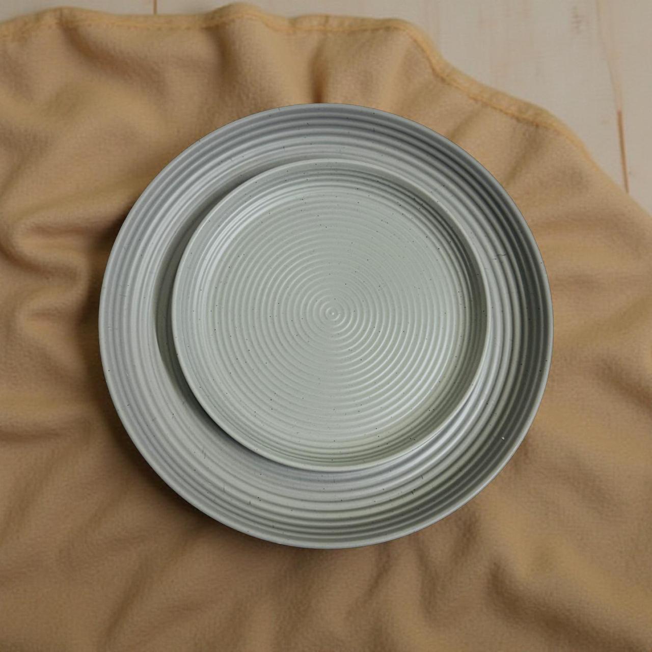 Two ceramic plates with textured design on a beige fabric background