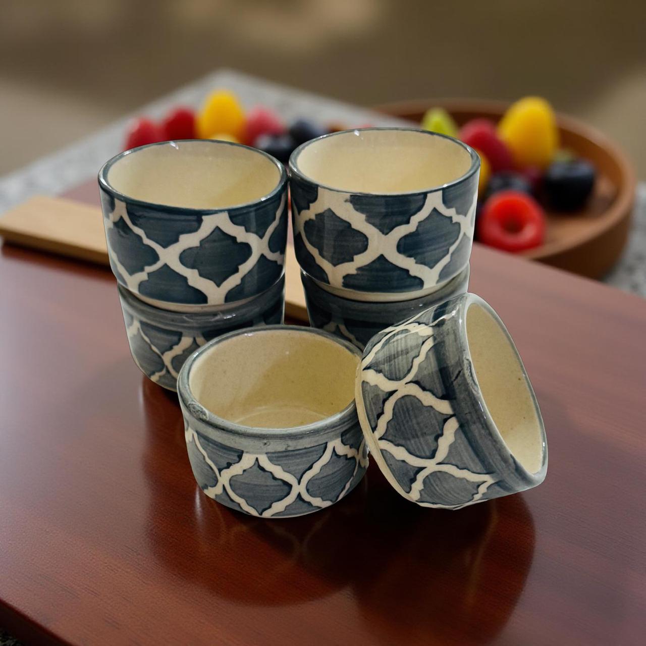 Set of four ceramic cups with blue and white pattern on a wooden surface.