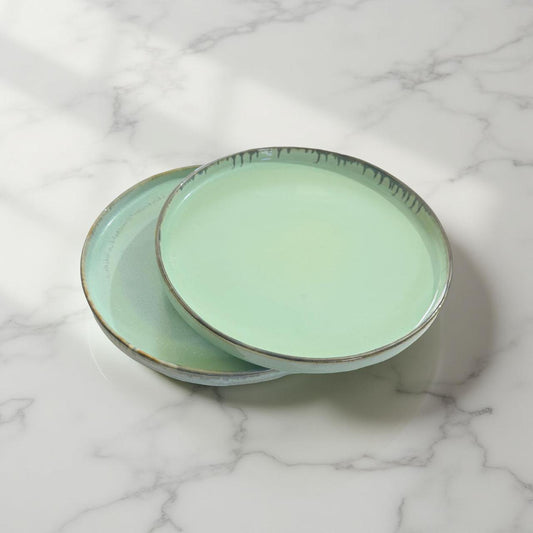 Two green ceramic plates stacked on a marble surface