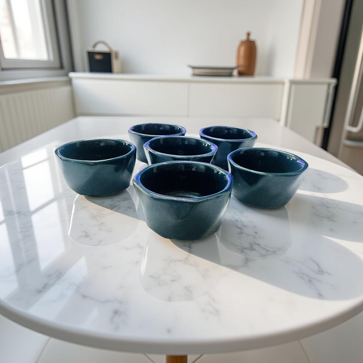Set of six blue ceramic bowls on a marble countertop