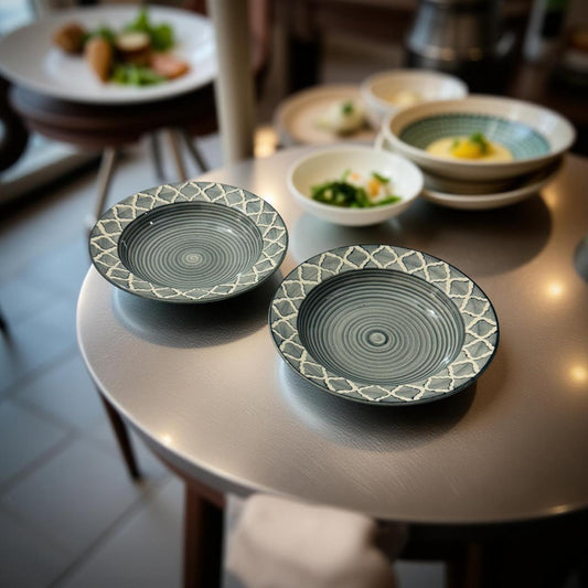 Two decorative ceramic plates on a metallic surface with blurred background