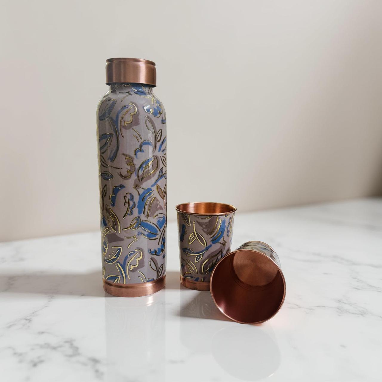Decorative water bottle with floral pattern and copper accents on a marble surface.