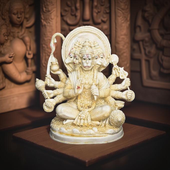 Statue of a deity with multiple arms and holding various objects on a wooden platform.