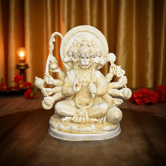 Statue of a deity with multiple arms and heads on a decorative platform with flowers and candles.