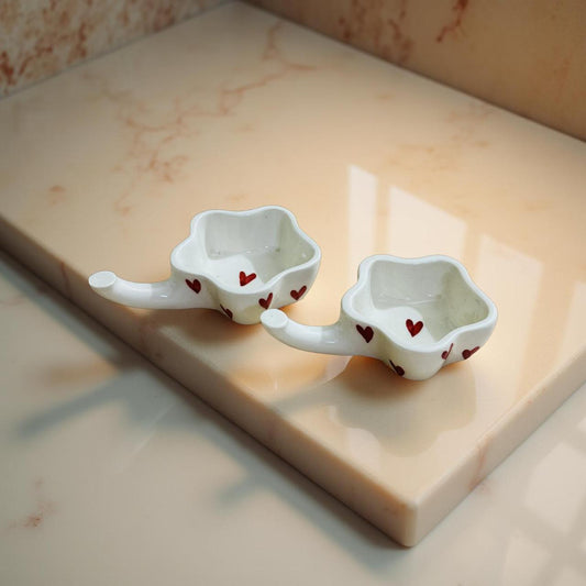 Two white ceramic bowls with red heart patterns on a marble surface