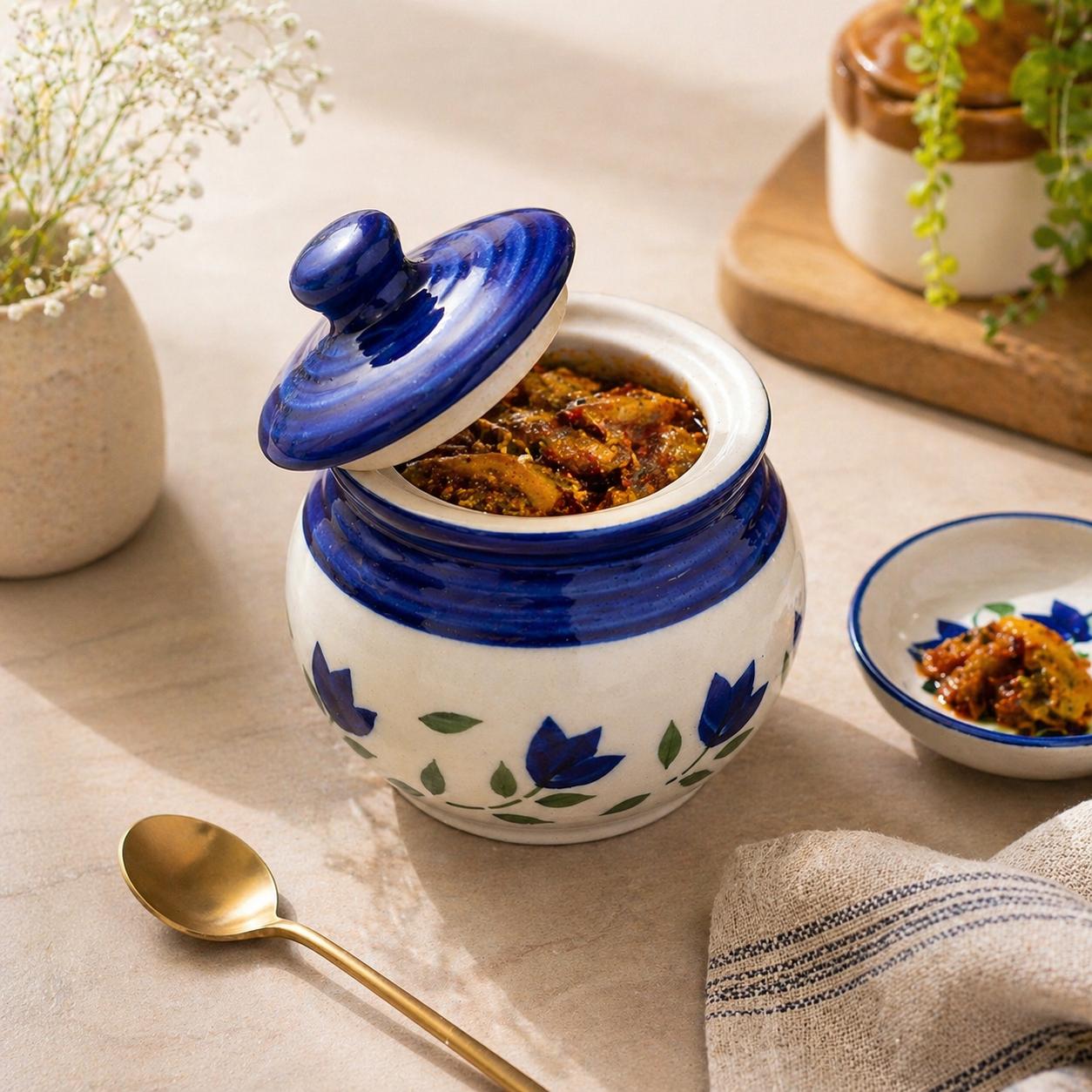 Decorative ceramic jar with blue floral patterns on a table with a spoon and small dish.