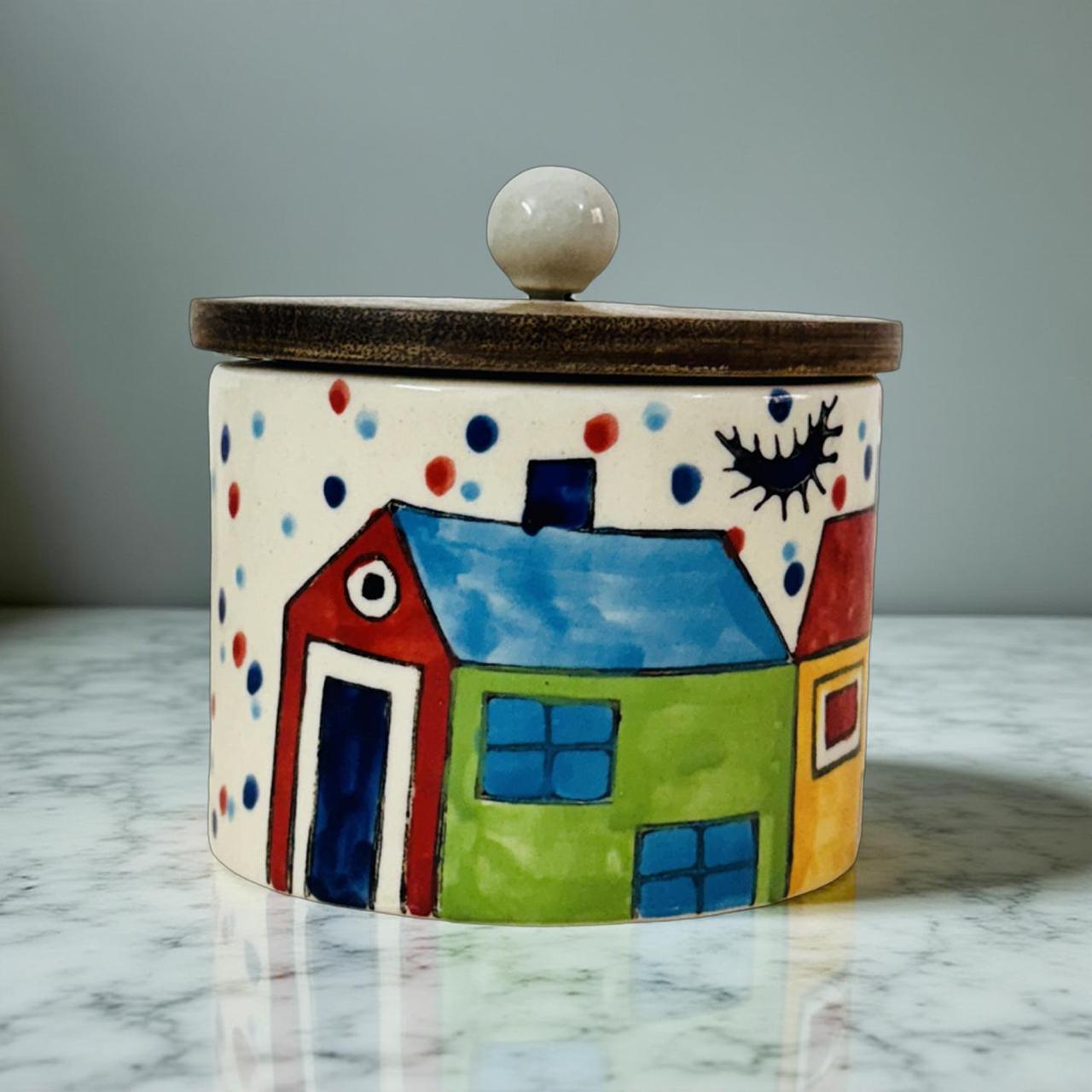 Decorative ceramic jar with a house design on a marble surface