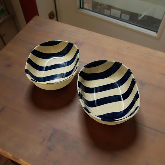 Two ceramic bowls with blue and white striped patterns on a wooden table.