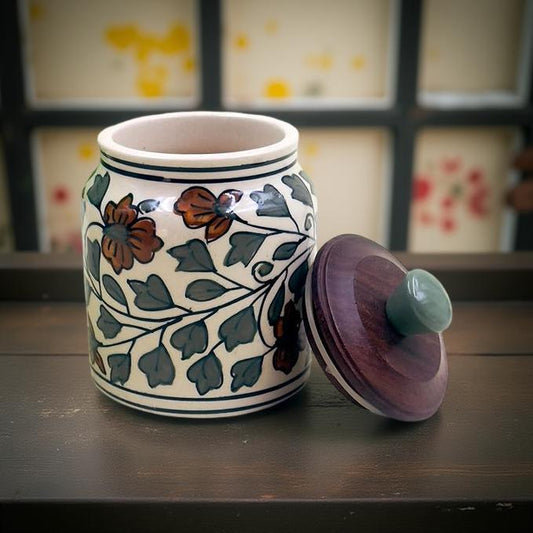 Ceramic jar with floral patterns and a wooden lid on a dark surface.