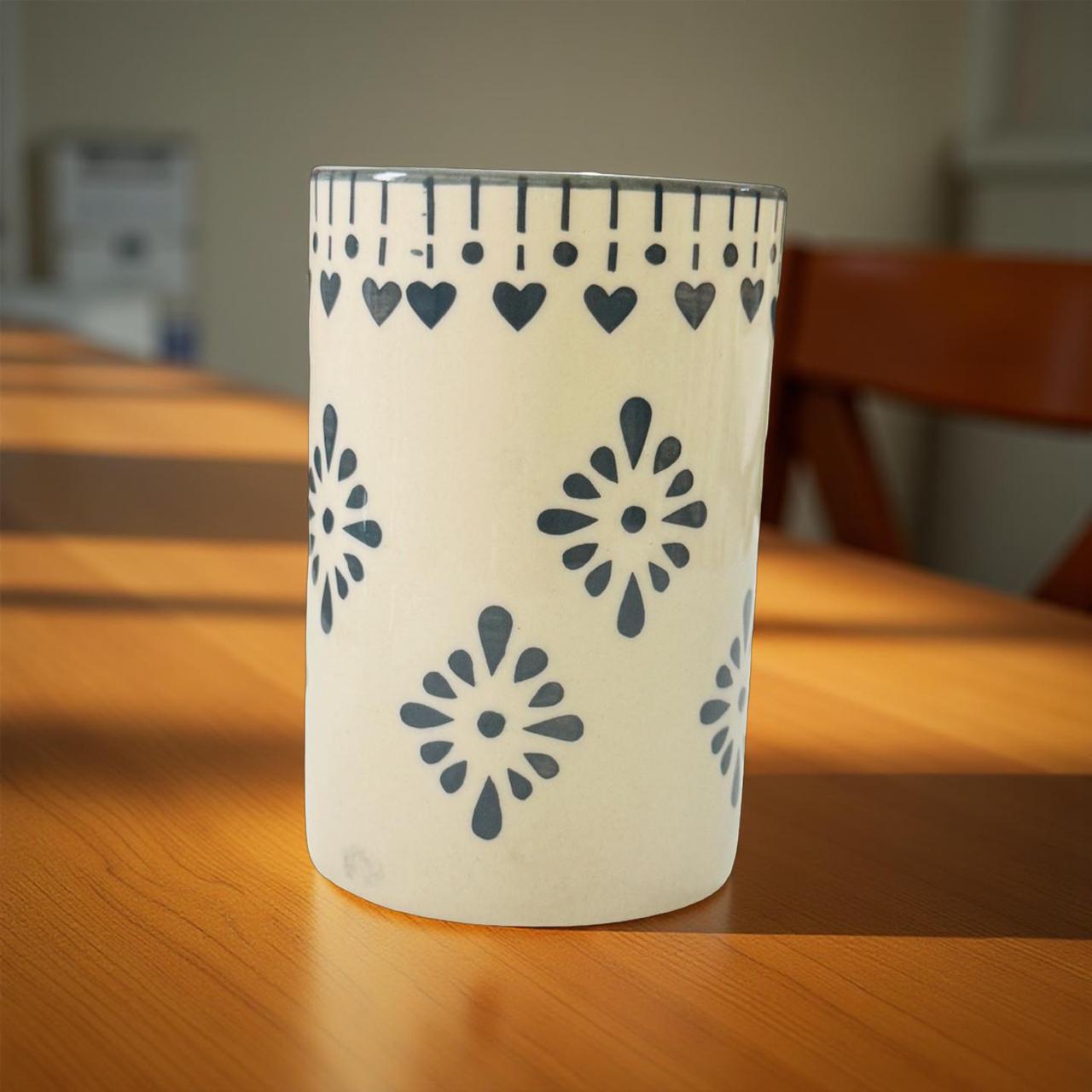 Decorative cylindrical container with floral patterns on a wooden surface