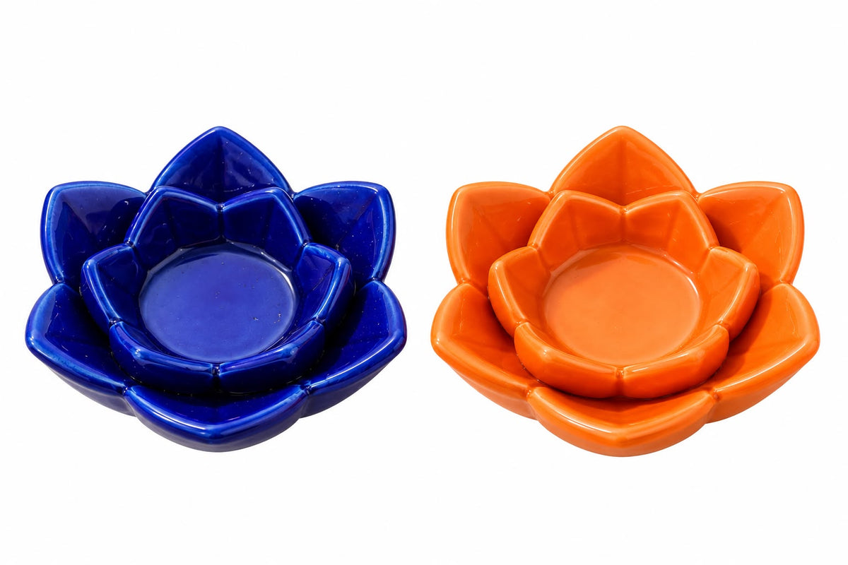 Two small lotus-shaped ceramic dishes or candle holders, one cobalt blue and one bright orange, shown side by side on a plain white background.