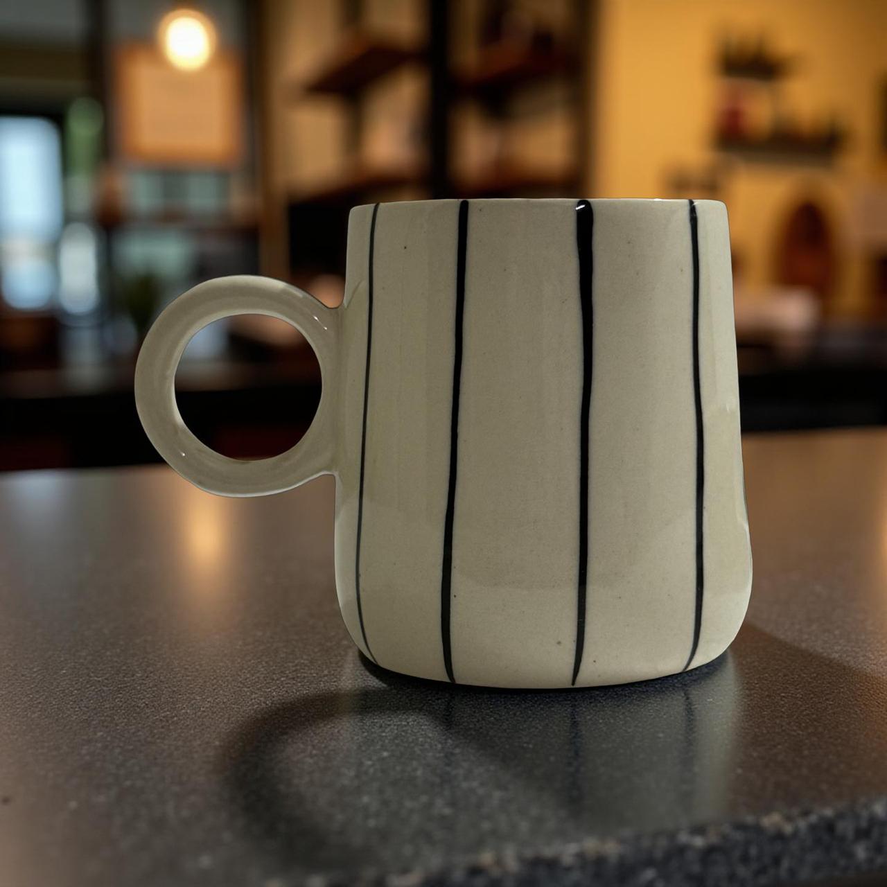 White mug with black stripes on a dark surface, blurred background