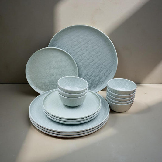 Set of light blue ceramic dinnerware including plates and bowls on a neutral background