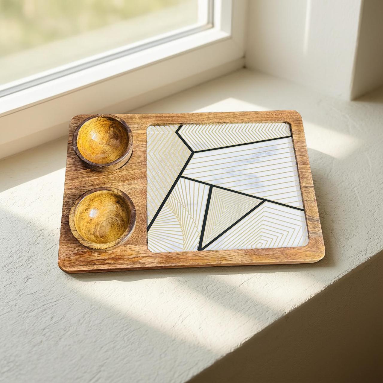 Wooden tray with geometric design and two wooden bowls on a light surface.