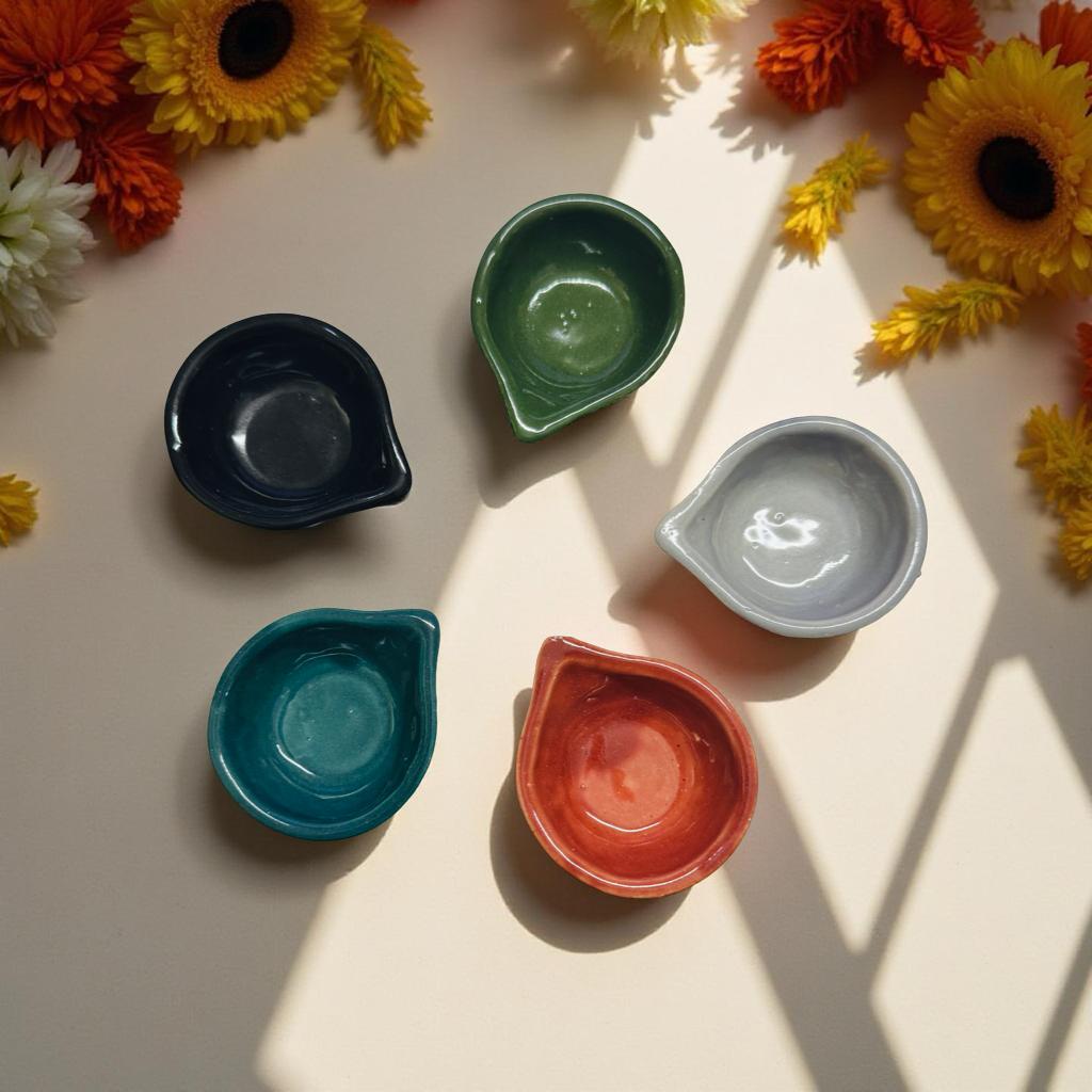 Five colorful ceramic bowls on a light surface with sunflowers around them.