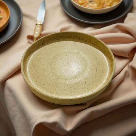 Beige ceramic plate on a beige cloth with a blurred background of other dishes.