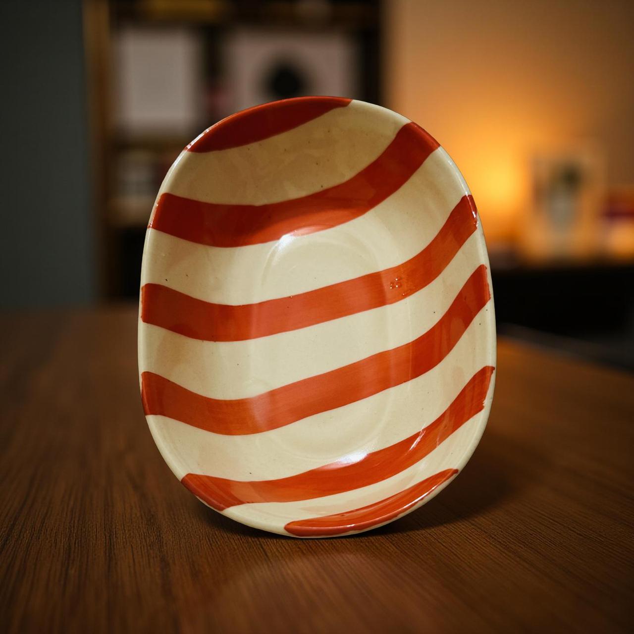 orange and white striped ceramic plate on a wooden surface with a blurred background