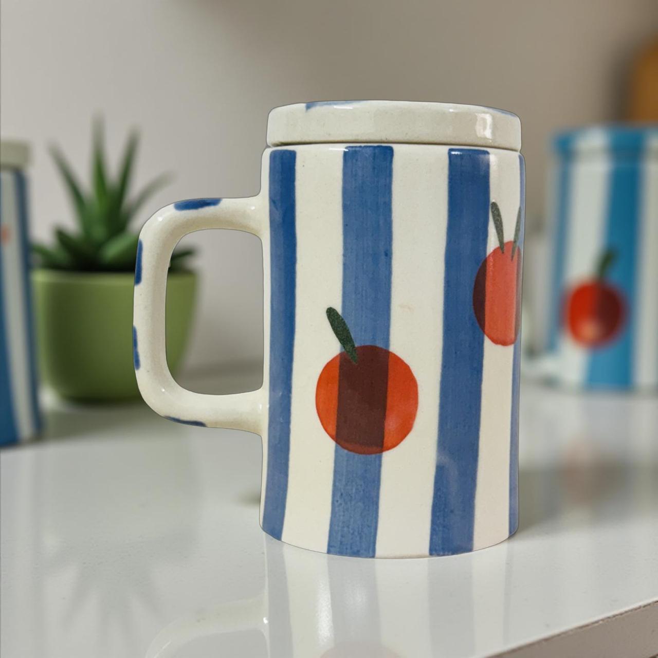 Mug with blue stripes and red apple design on a white surface.