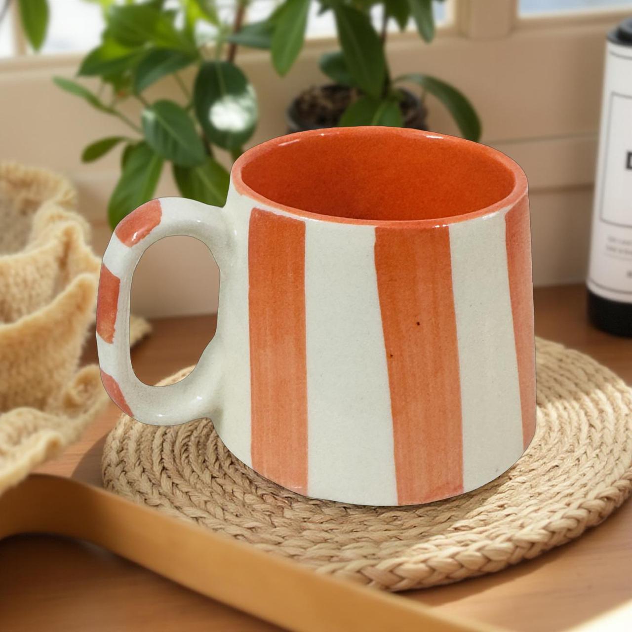 Ceramic mug with orange and white stripes on a woven mat