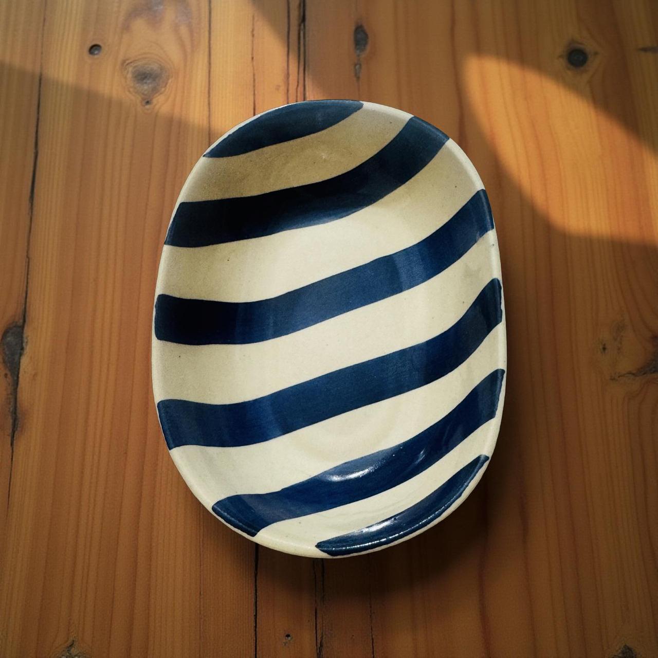 Ceramic plate with blue and white stripes on a wooden surface