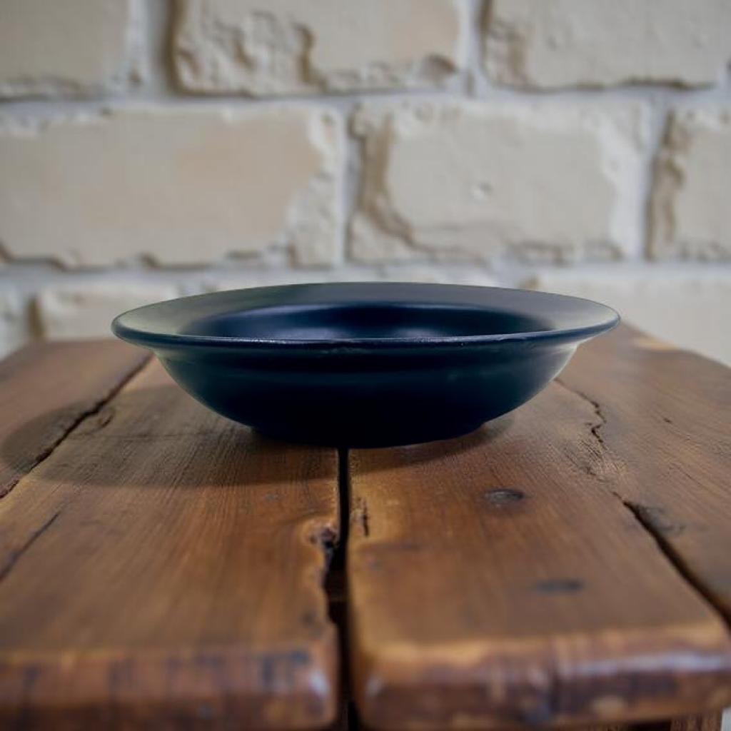 Black bowl on a wooden surface with a rustic brick wall background