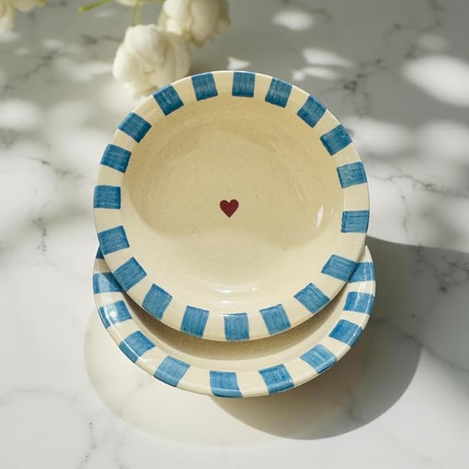 Ceramic bowl with blue striped rim and red heart on a marble surface