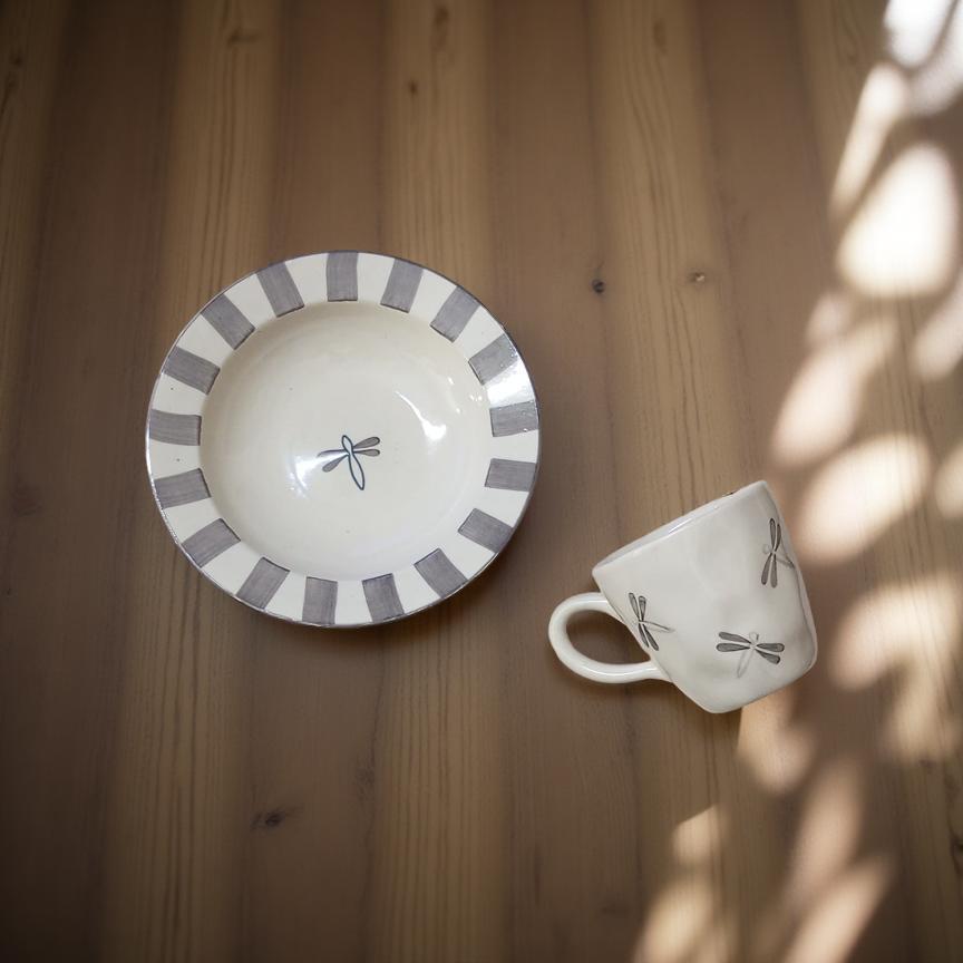 Ceramic cup and saucer with decorative patterns on a wooden surface