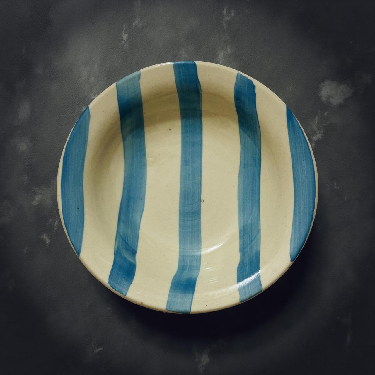 Ceramic plate with blue stripes on a dark background