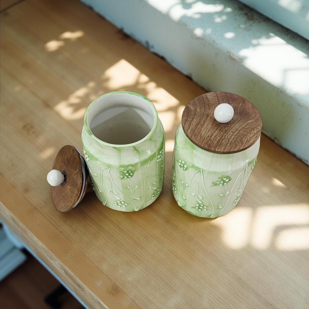 Two ceramic containers with wooden lids on a wooden surface.