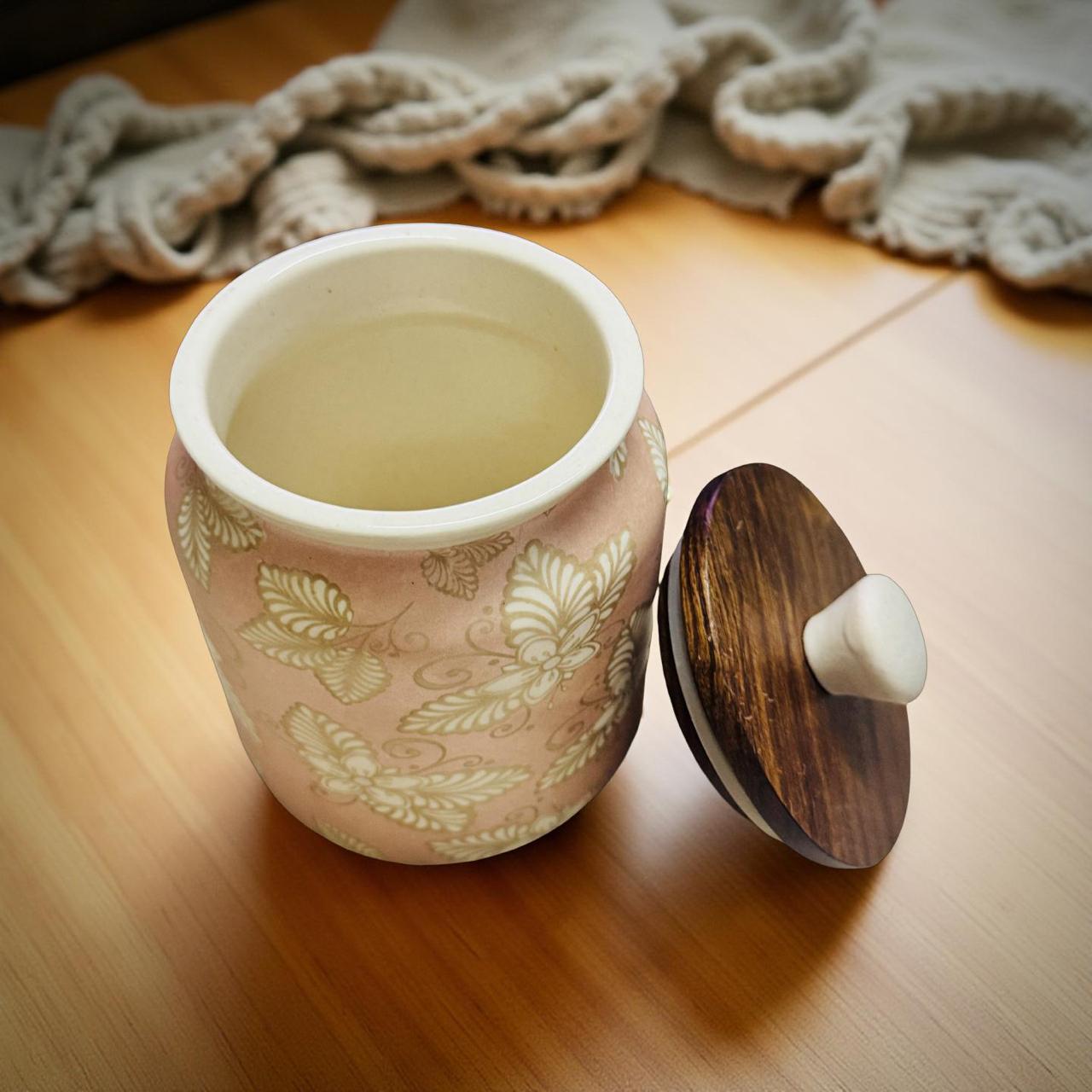 pink ceramic jar with wooden lid kept on a wooden surface