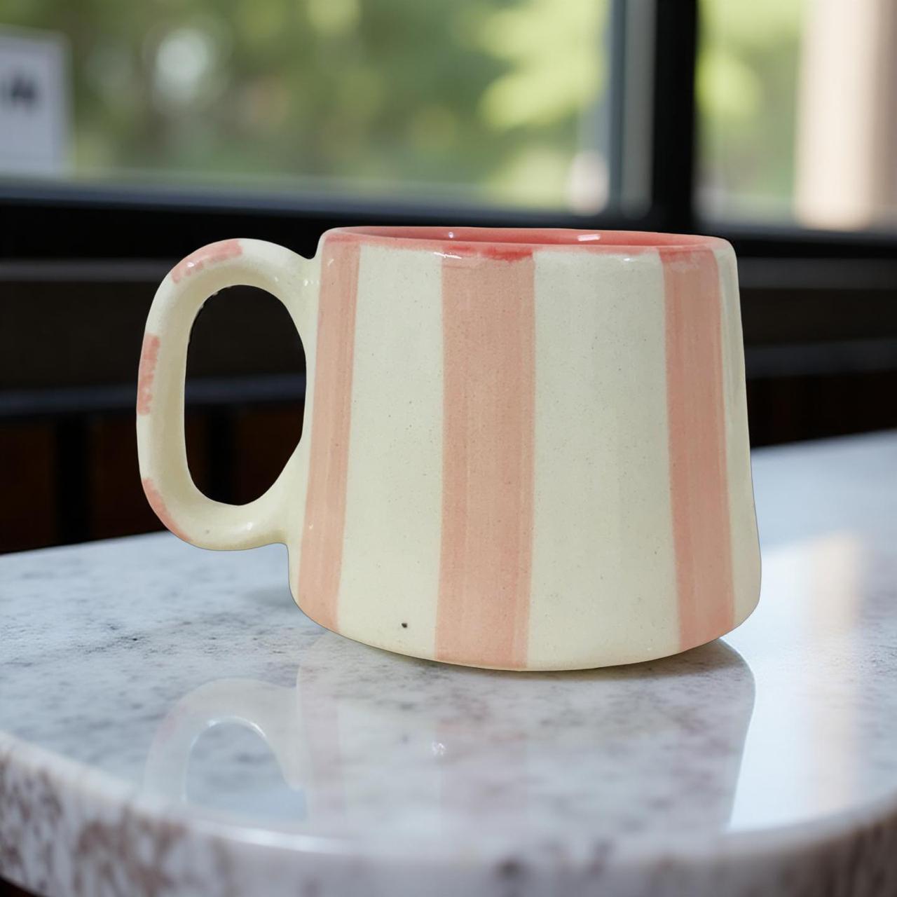 Striped ceramic mug on a marble surface with a blurred natural background