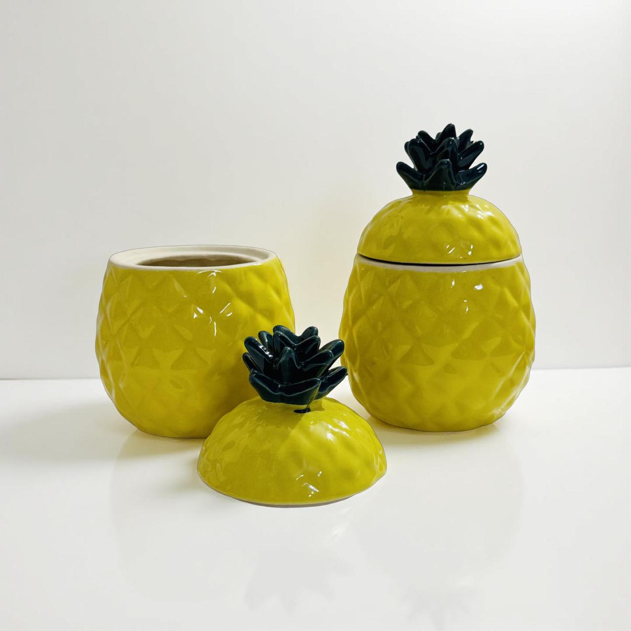 Set of three pineapple-shaped ceramic jars with black accents on a white background
