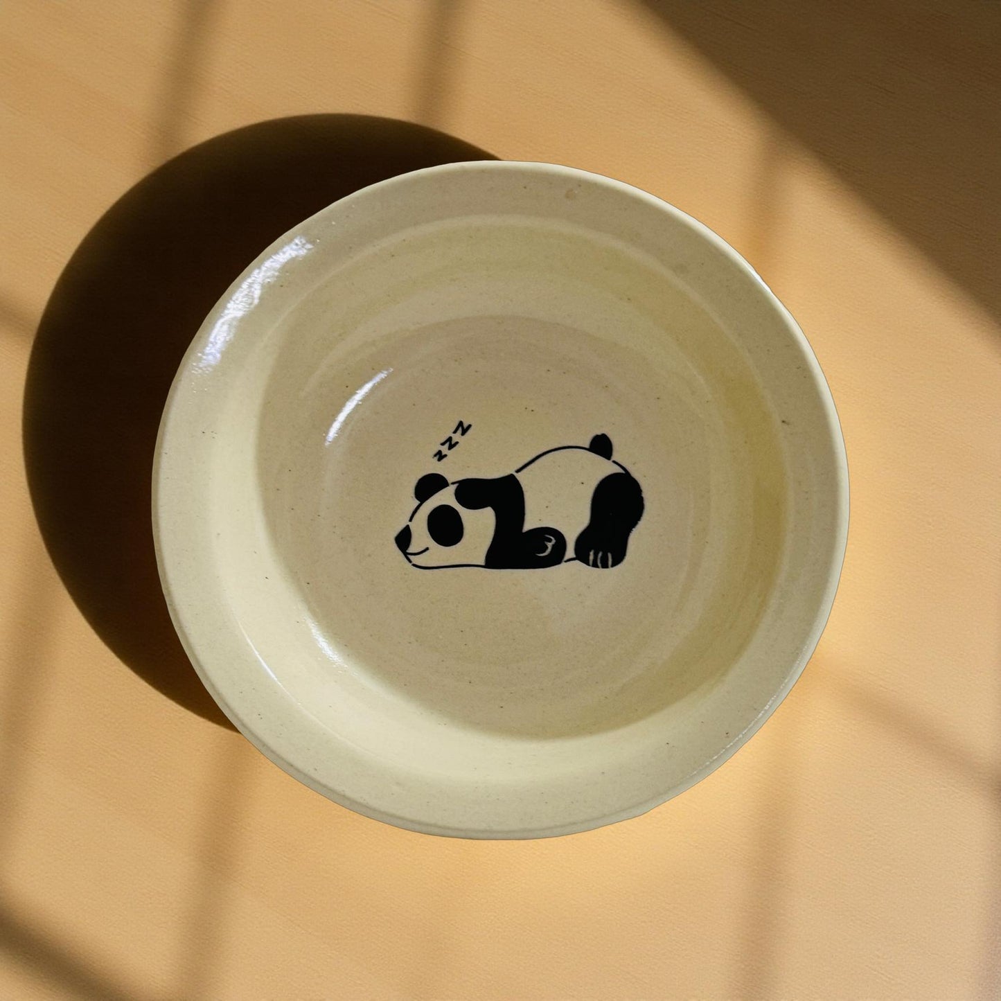 Ceramic bowl with a panda design on a beige background