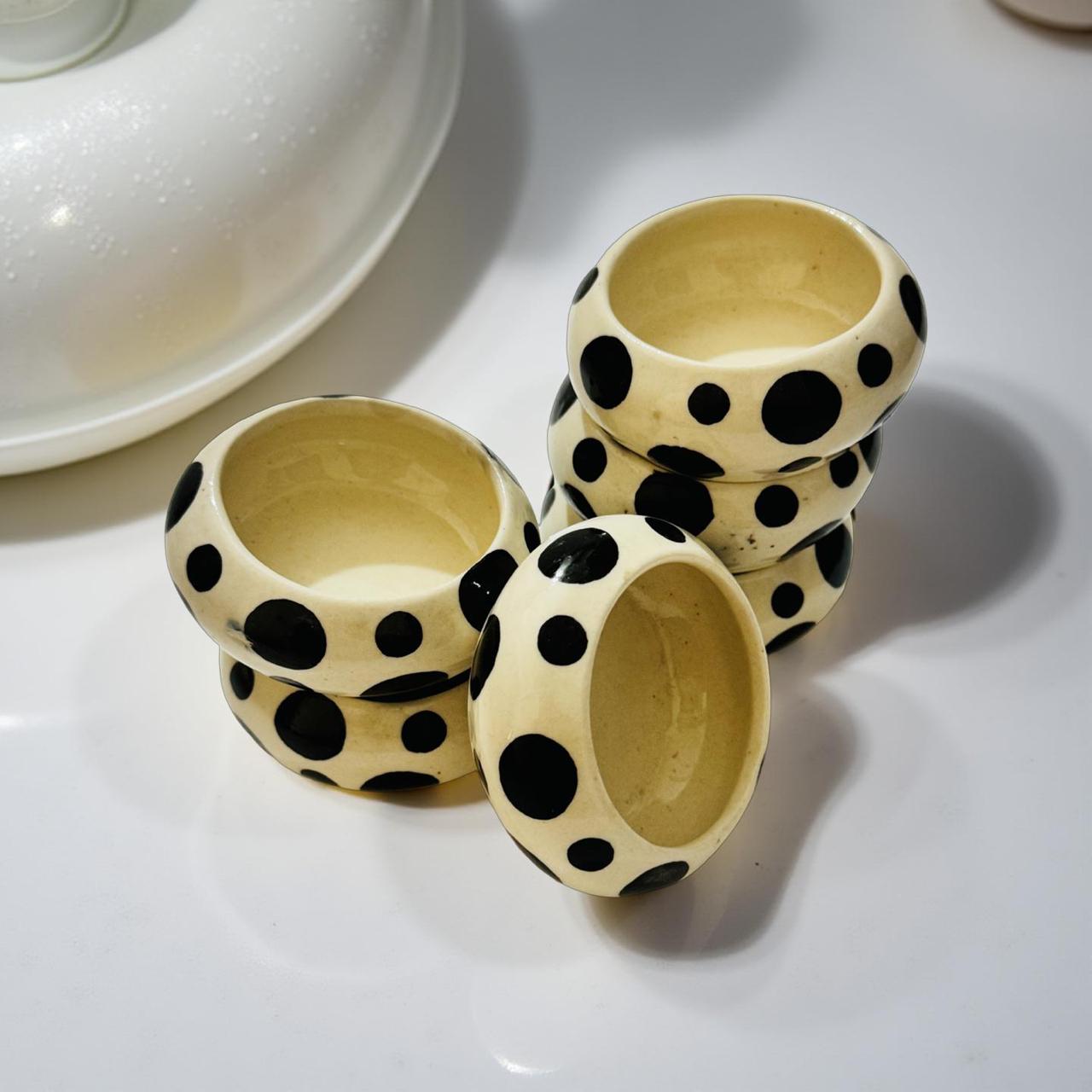 Three ceramic cups with black polka dot patterns on a white surface