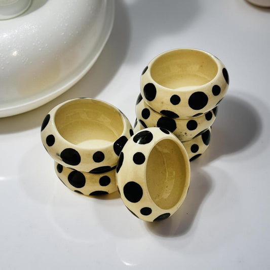 Three ceramic cups with black polka dot patterns on a white surface
