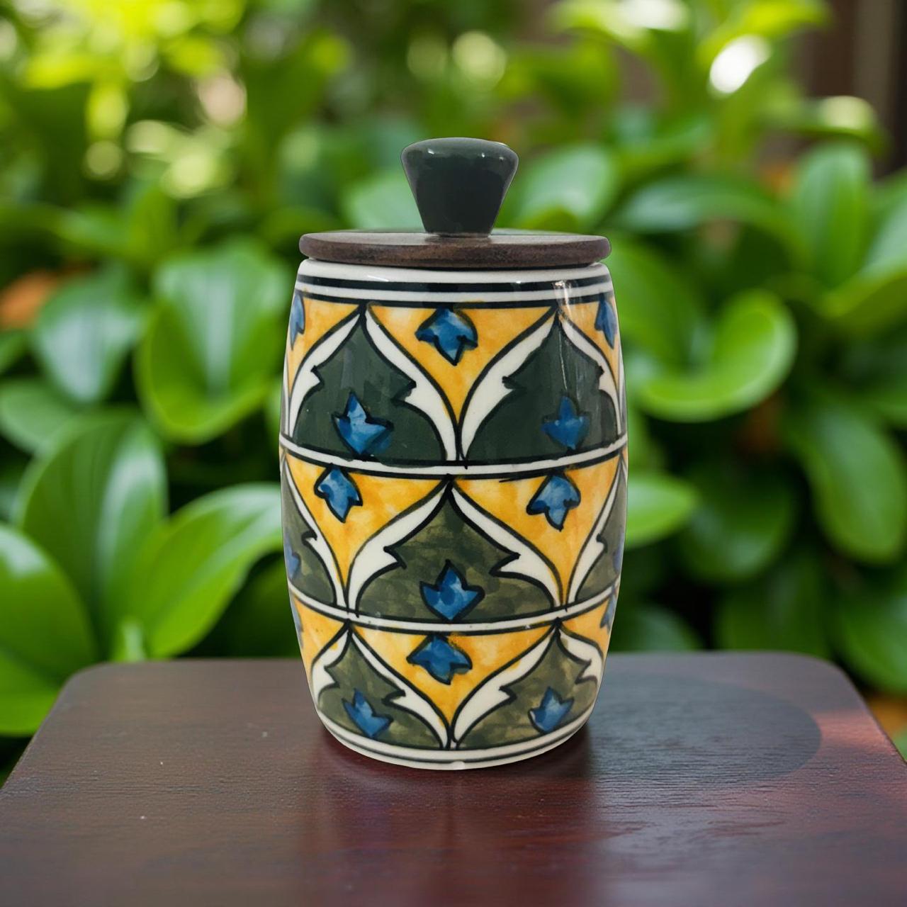 Decorative ceramic jar with geometric pattern on a wooden surface with green foliage in the background